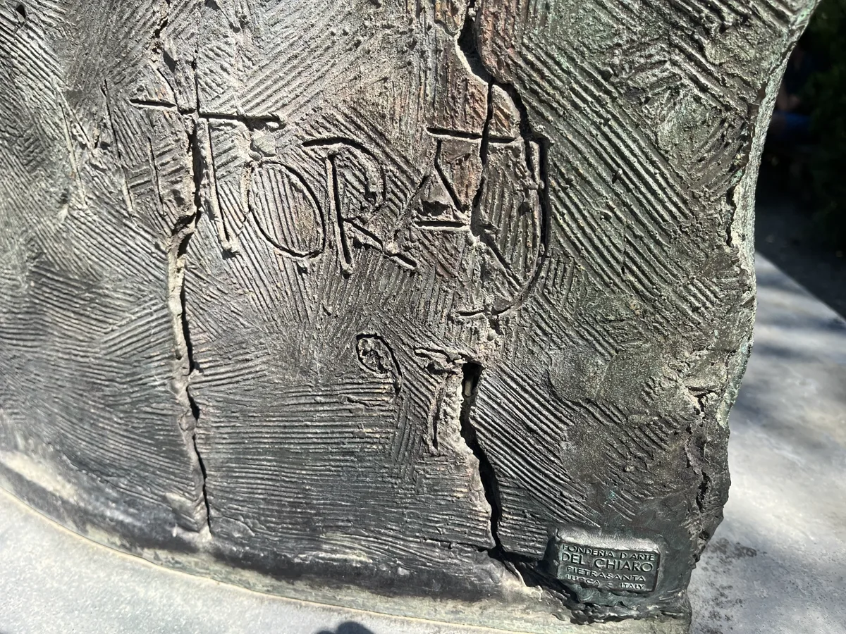 Igor Mitoraj's incised signature on the base of Tindaro Screpolato — MITORAJ 97 carved into the bronze between areas of fissured patina