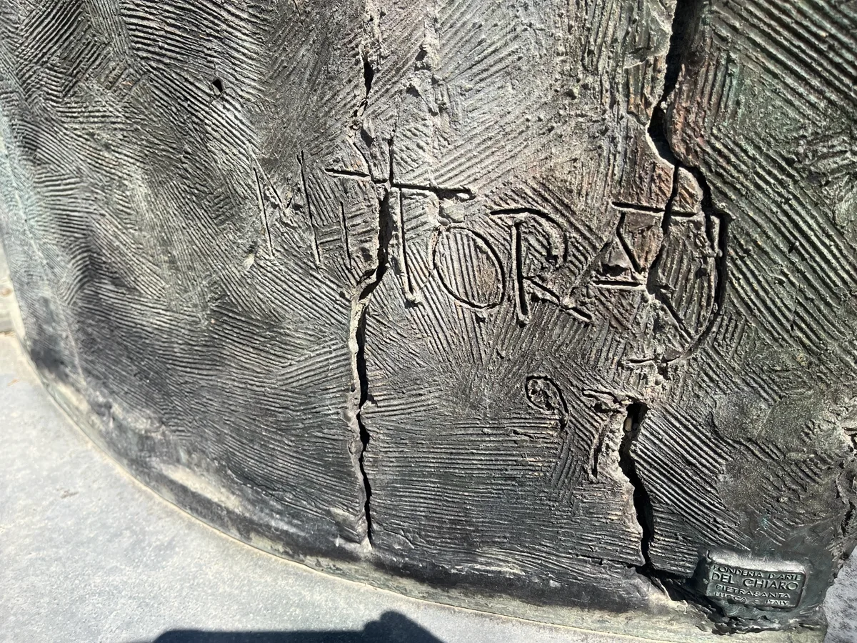 Angled close-up of the MITORAJ 97 signature on the base of Tindaro Screpolato in the Boboli Gardens — evidence of the artist's own hand on the finished cast
