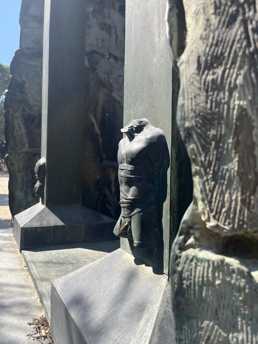 Detail of a smaller Mitoraj bronze figure — a bandaged torso in an architectural niche seen at close range with dramatic side lighting, photographed on the same Florence visit