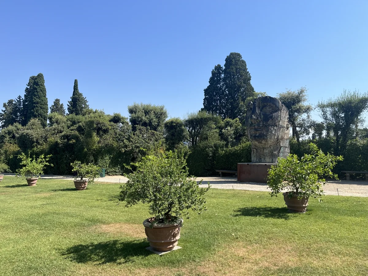 Landscape view across the Boboli lemon-tree lawn with terracotta pots in the foreground and the cracked profile of Tindaro Screpolato visible in the middle distance