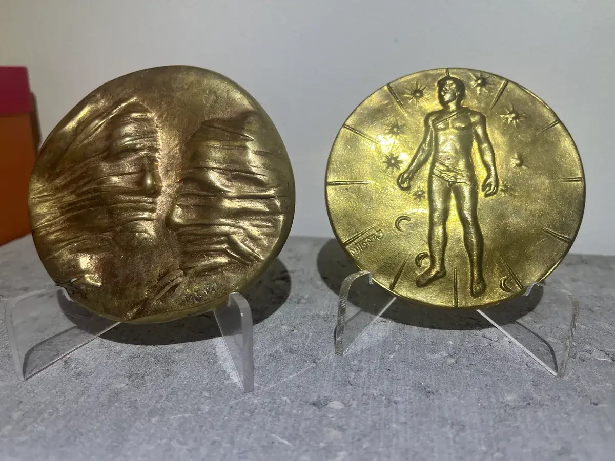 La Conversation — Igor Mitoraj, both medals on stands — obverse showing conversation relief, reverse with standing figure