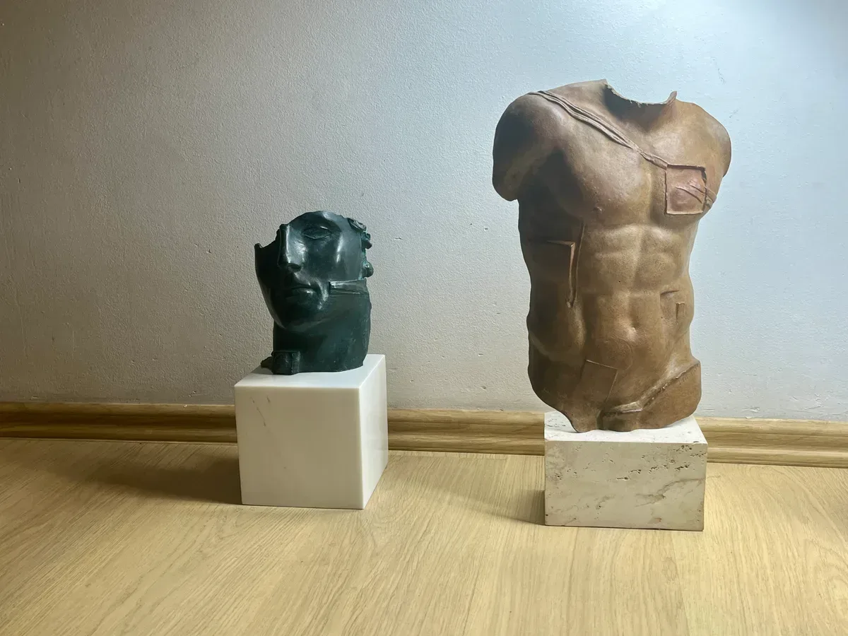 Persée (1988) — Igor Mitoraj, brown patina bronze torso with small green-black bronze head on marble base, alternate angle showing both works in natural daylight, private collection Warsaw
