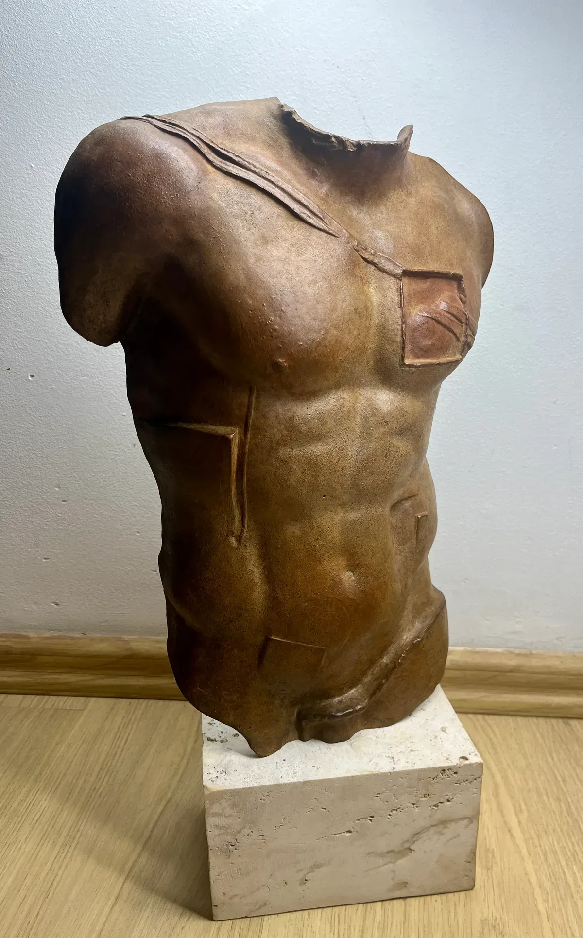 Persée (1988) — Igor Mitoraj, brown patina bronze torso, clean three-quarter portrait view from low angle on travertine plinth, full musculature and chest inset visible, private collection Warsaw