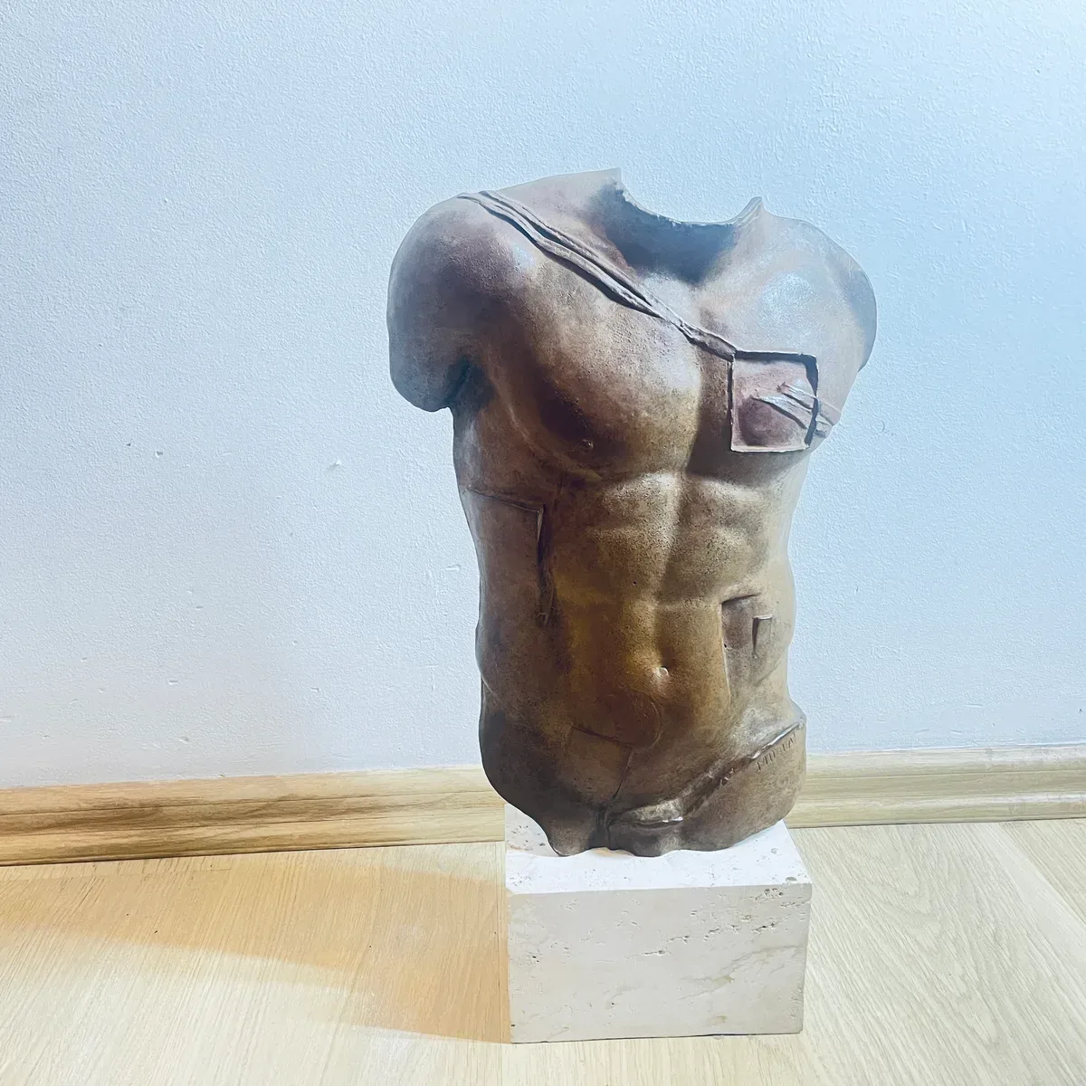 Persée (1988) — Igor Mitoraj, brown patina bronze torso on travertine base, three-quarter front view, private collection