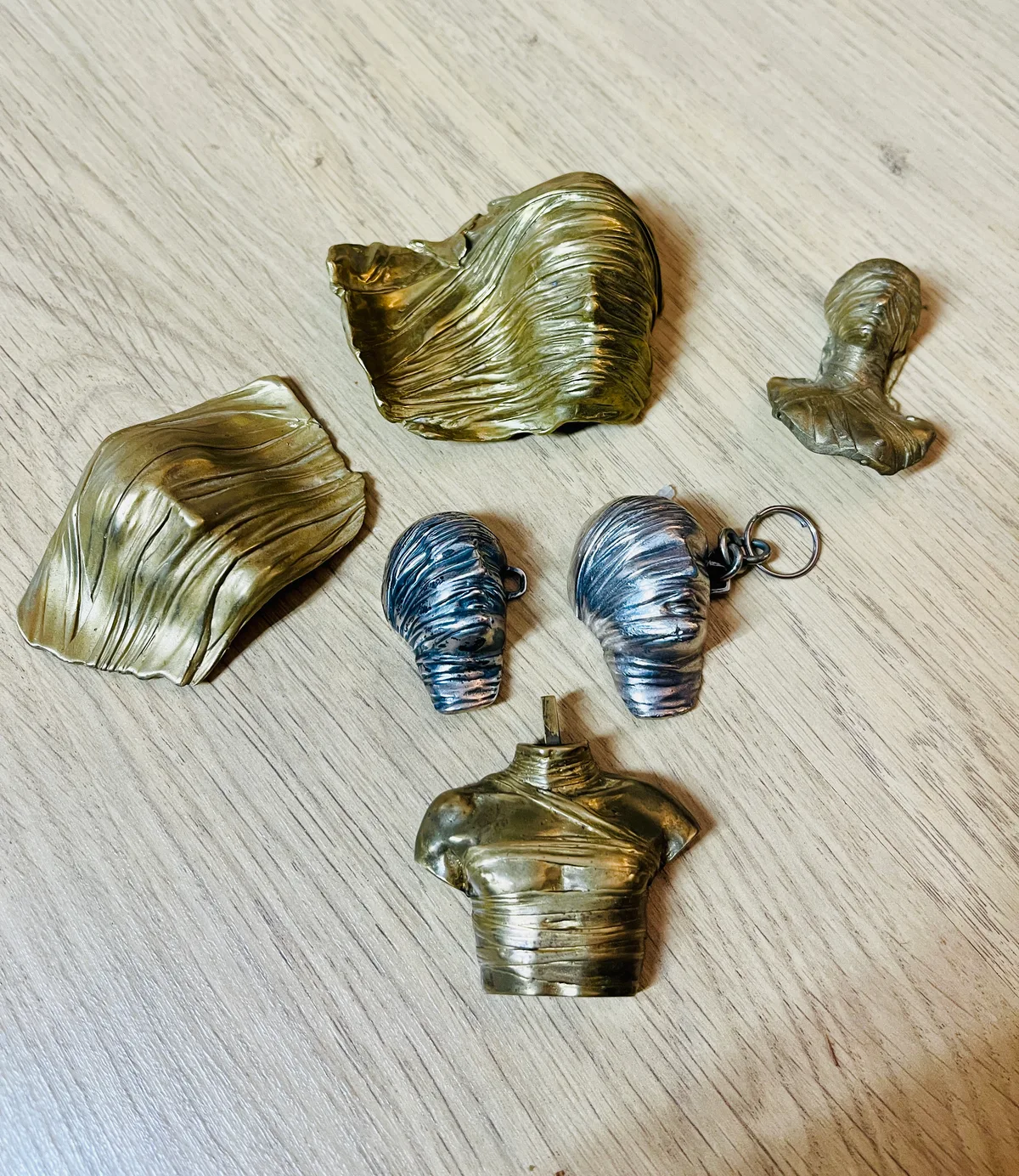 Testa Addormentata silver pendants shown among Mitoraj gilt-bronze miniature Corazza and torso studies — comparative study group